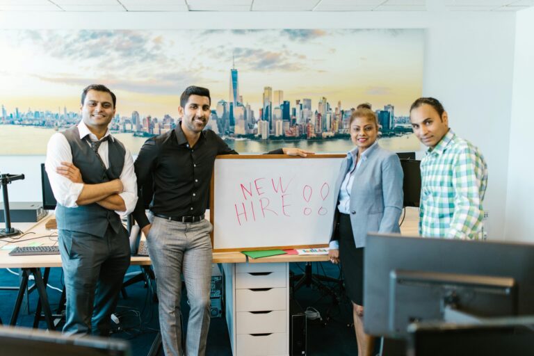Diverse team standing with 'New Hire' sign, symbolizing collaboration and teamwork.