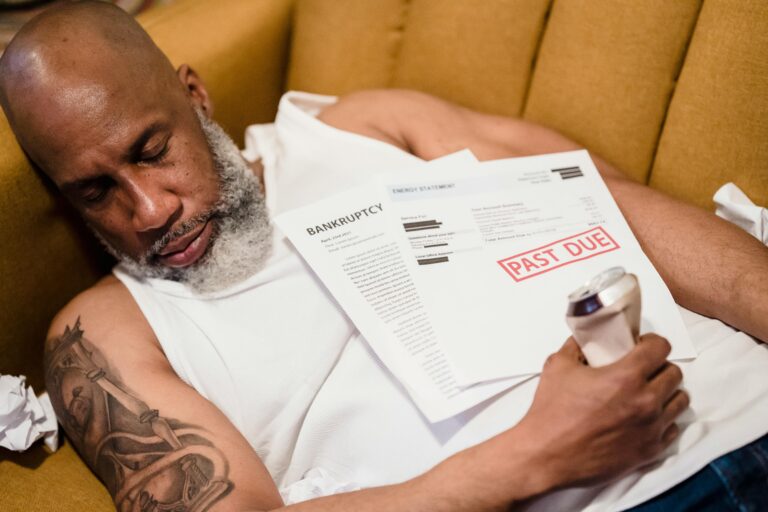 Sleeping man with financial documents, symbolizing stress and bankruptcy.